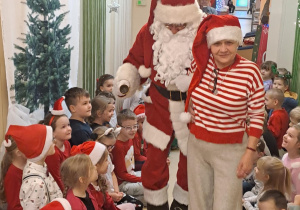 Na zdjęciu widać dzieci i Św Mikołaja który wręcza prezenty.