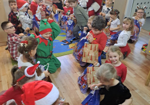 Na zdjęciu widać dzieci i Św Mikołaja który wręcza prezenty.