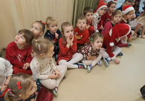 Na zdjęciu widać dzieci i Św Mikołaja który wręcza prezenty.