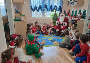 Na zdjęciu widać dzieci i Św Mikołaja który wręcza prezenty.