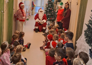 Na zdjęciu widać dzieci i Św Mikołaja który wręcza prezenty.