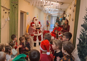 Na zdjęciu widać dzieci i Św Mikołaja który wręcza prezenty.
