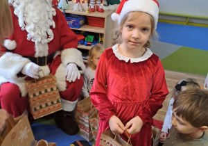 Na zdjęciu widać dzieci i Św Mikołaja który wręcza prezenty.