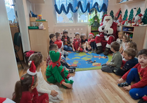 Na zdjęciu widać dzieci i Św Mikołaja który wręcza prezenty.