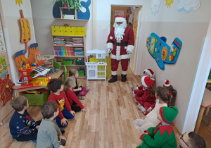 Na zdjęciu widać dzieci i Św Mikołaja który wręcza prezenty.