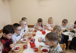 Na zdjęciu widać dzieci przy wigilijnym które jedzą obiad.