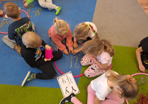 Na zdjęciu widać dzieci które piszą literę y,Y z makaronu.