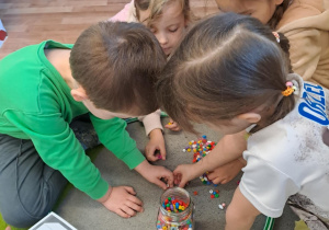 Na zdjęciu widać dzieci które piszą literę y,Y z makaronu.