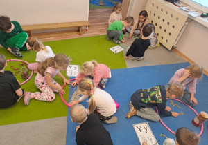 Na zdjęciu widać dzieci które piszą literę y,Y z makaronu.