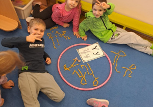 Na zdjęciu widać dzieci które piszą literę y,Y z makaronu.