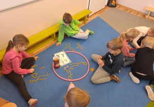 Na zdjęciu widać dzieci które piszą literę y,Y z makaronu.