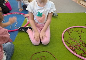 Na zdjęciu widać dziewczynkę która pisze literę y,Y z makaronu.