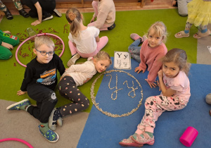 Na zdjęciu widać dzieci które piszą literę y,Y z makaronu.