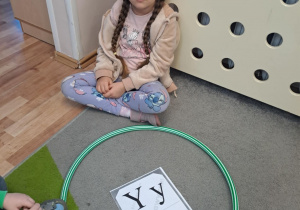 Na zdjęciu widać dziewczynkę która pisze literę y,Y z makaronu.