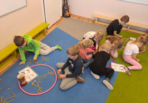 Na zdjęciu widać dzieci które piszą literę y,Y z makaronu.