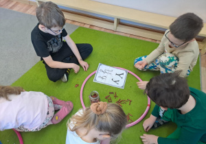 Na zdjęciu widać dzieci które piszą literę y,Y z makaronu.