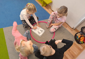 Na zdjęciu widać dzieci które piszą literę y,Y z makaronu.