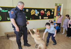 Na zdjęciu widać Pana z psem ze Straży Miejskiej oraz dziecko..