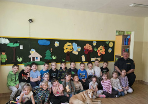 Na zdjęciu widać Pana z psem ze Straży Miejskiej oraz dzieci.