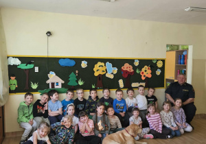 Na zdjęciu widać Pana z psem ze Straży Miejskiej oraz dzieci.