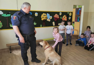 Na zdjęciu widać Pana z psem ze Straży Miejskiej oraz dziecko.
