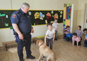 Na zdjęciu widać Pana z psem ze Straży Miejskiej oraz dziecko.