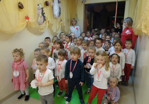 Duża grupa dzieci stoi w holu przedszkola. Większość z nich jest ubrana w barwy narodowe.