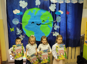 Dzieci stoją z dyplomami na tle obrazka kuli ziemskiej i napisu Na ratunek Ziemi