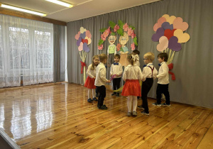 Dzieci stoją w kole trzymając kolorowe szarfy.