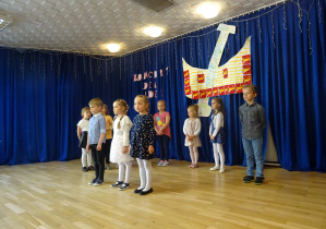 Dzieci stoją na tle dekoracji z łódką i napisem Koncert dla Łodzi