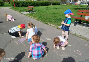 Dzieci rysują kredą na betonowym boisku