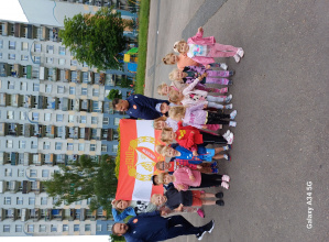 Grupa dzieci stoi w gromadce w tle flaga z herbem Łódzkiego Widzewa
