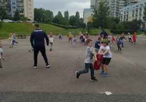 Dzieci biegają i ganiają się podając sobie koszulkę (znacznik)