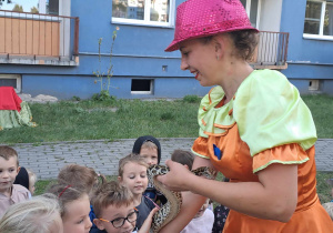 Na zdjęciu są pokazane dzieci które oglądają i dotykają węża pokazanego przez Panią z cyrku.