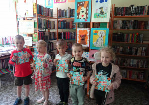 Czworo dzieci stoi w szeregu trzymając w rękach książki, które są nagrodami w konkursie.